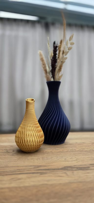 Twee vazen, een geel en een blauw, met droogbloemen, op een houten oppervlak.